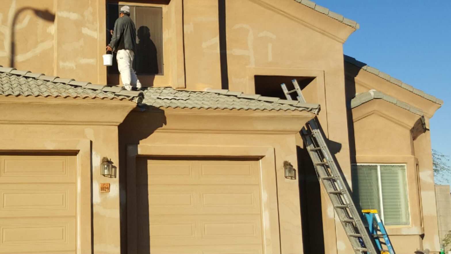 painting house exterior with a ladder